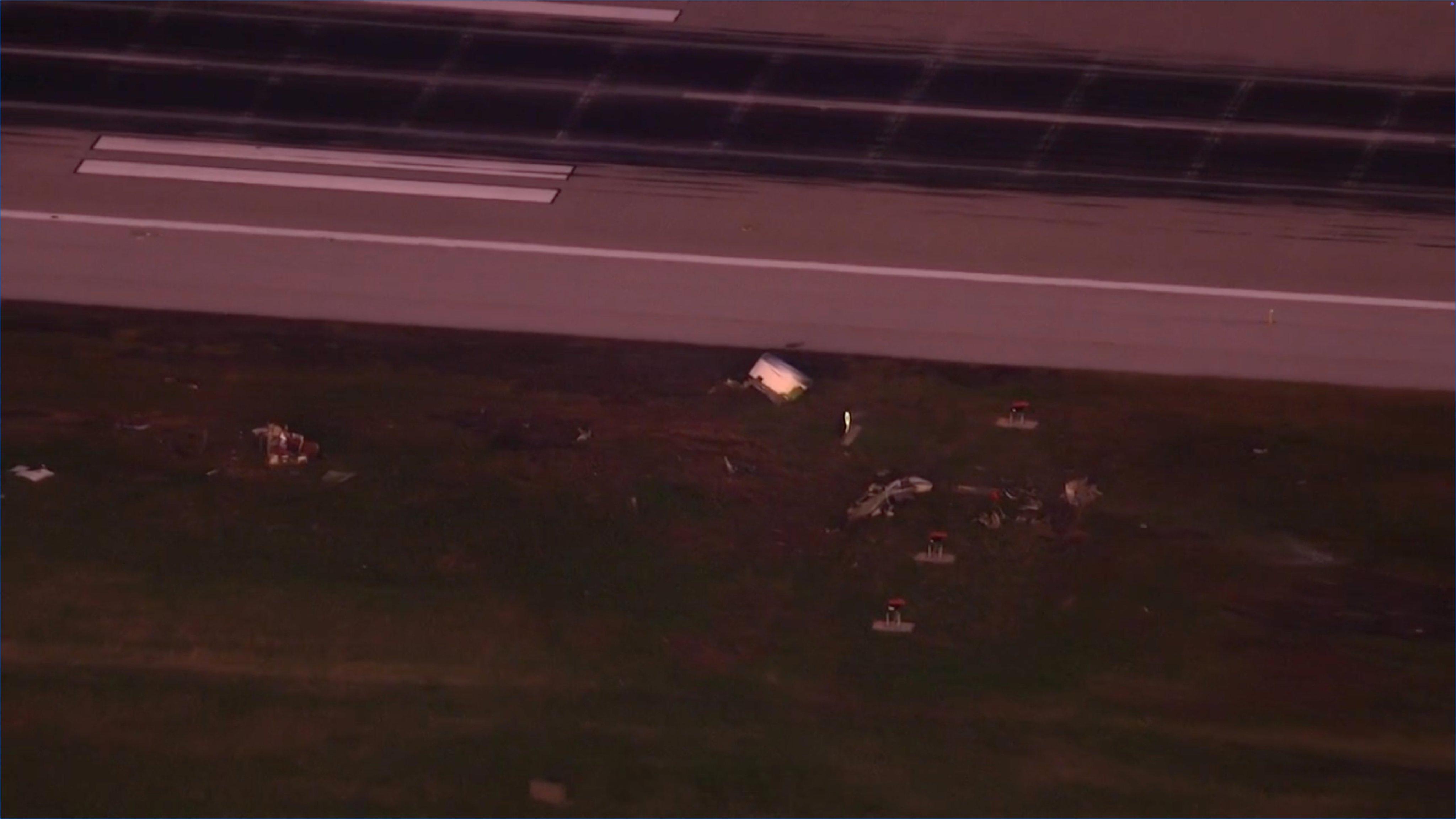 机场跑道上的MD-11发动机罩碎片，以及附近受损的建筑物美国一机场发生飞机坠毁事