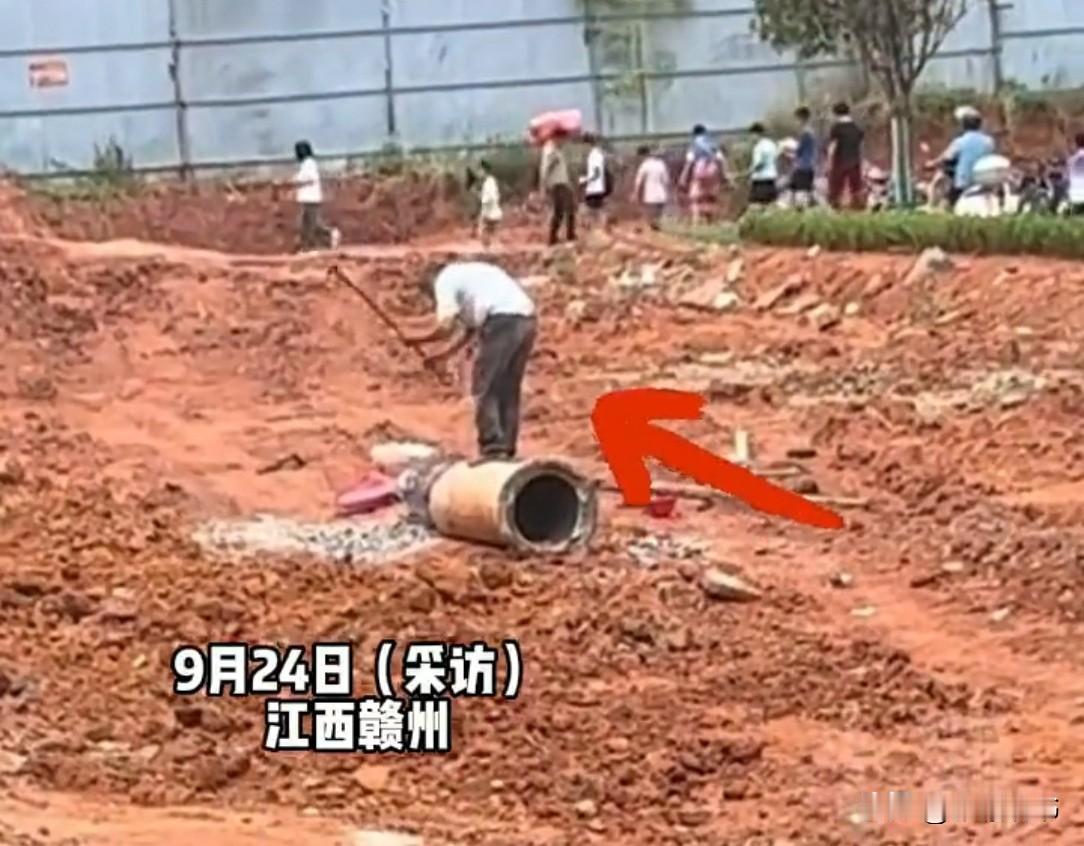 江西一工地上，大爷正费劲敲废弃水泥管。突然一小伙喊“让一下”，大爷纳闷：边上也没