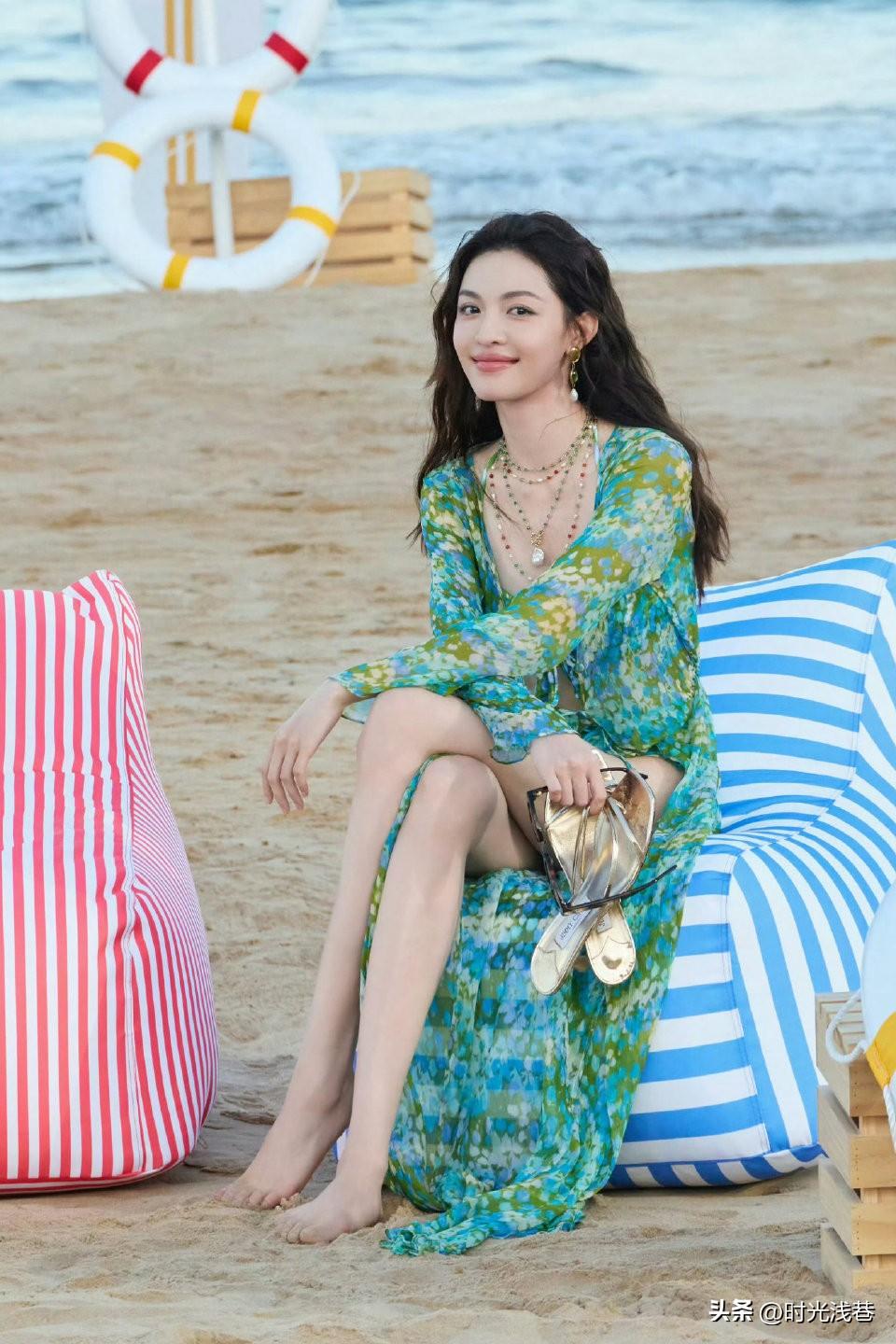 海边沙滩上的钟楚曦，手提高跟凉鞋，光脚踩在松软的沙滩上。笑容甜美如春风般温暖！