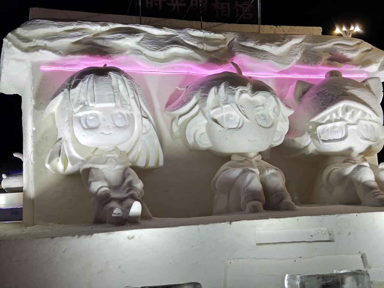 今日分享随手拍照片夜幕下，卡通雪雕被暖光与粉紫色灯带温柔包裹，圆滚滚的Q版人物憨