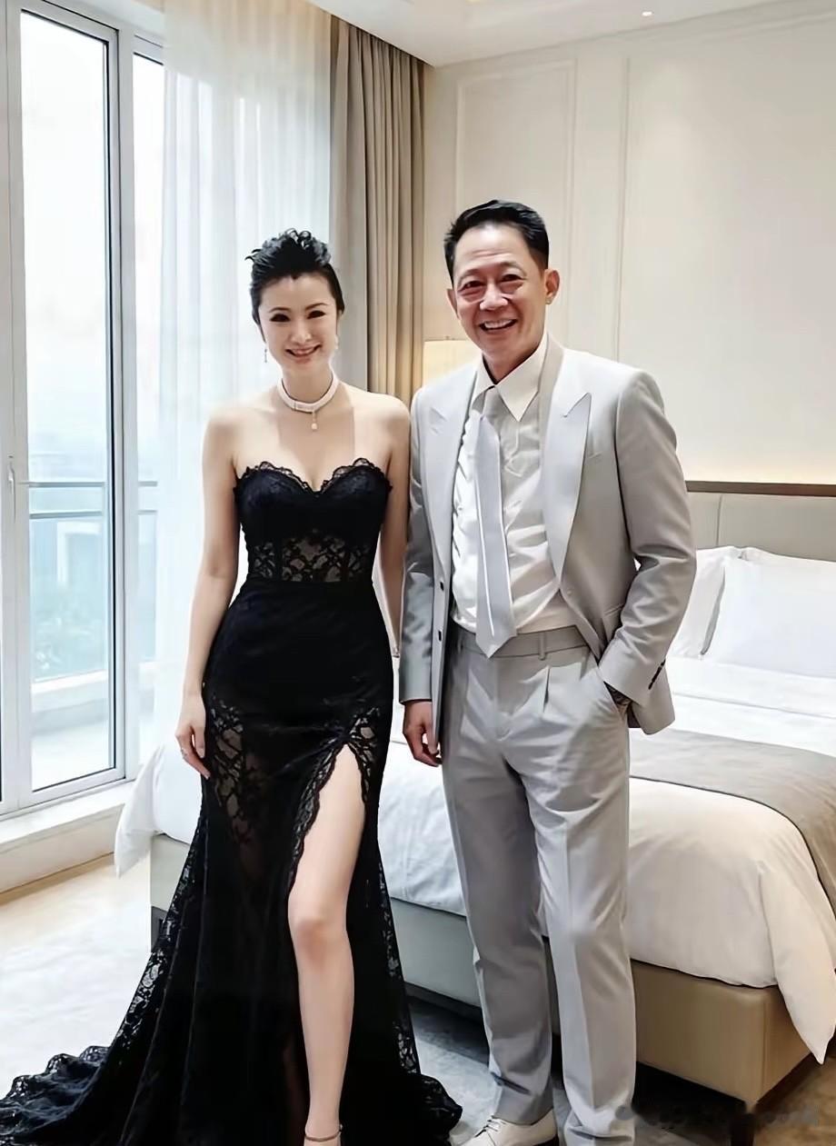 穿着一身灰色西装的是演员王志文，那旁边穿黑色礼服裙的美女是谁呢？王志文出道30多