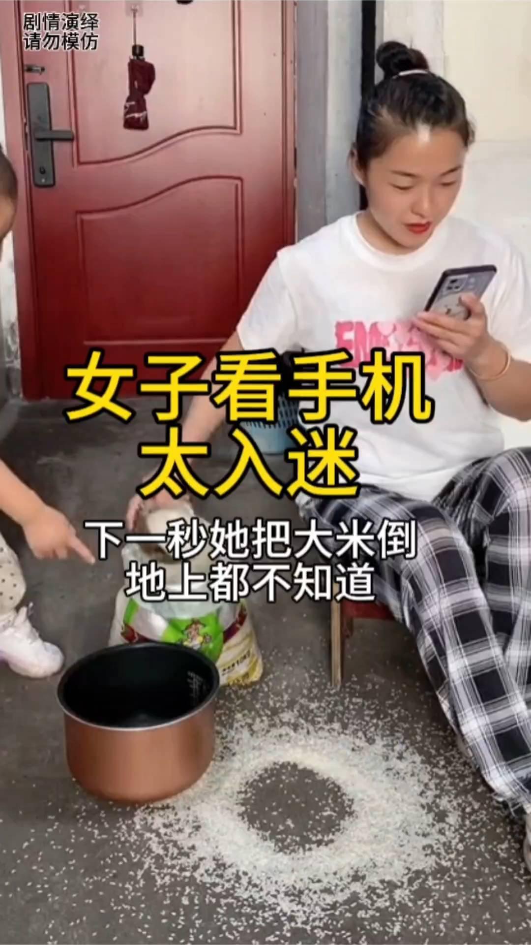 女子看手机太入迷，下一秒她把大米倒地上都不知道。
中午做饭时间到了，女子坐在椅子