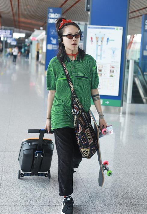 窦靖童不愧是天后的女儿，身上穿的全都是潮牌个性风，头上戴着红绳，身上穿的绿衣，红