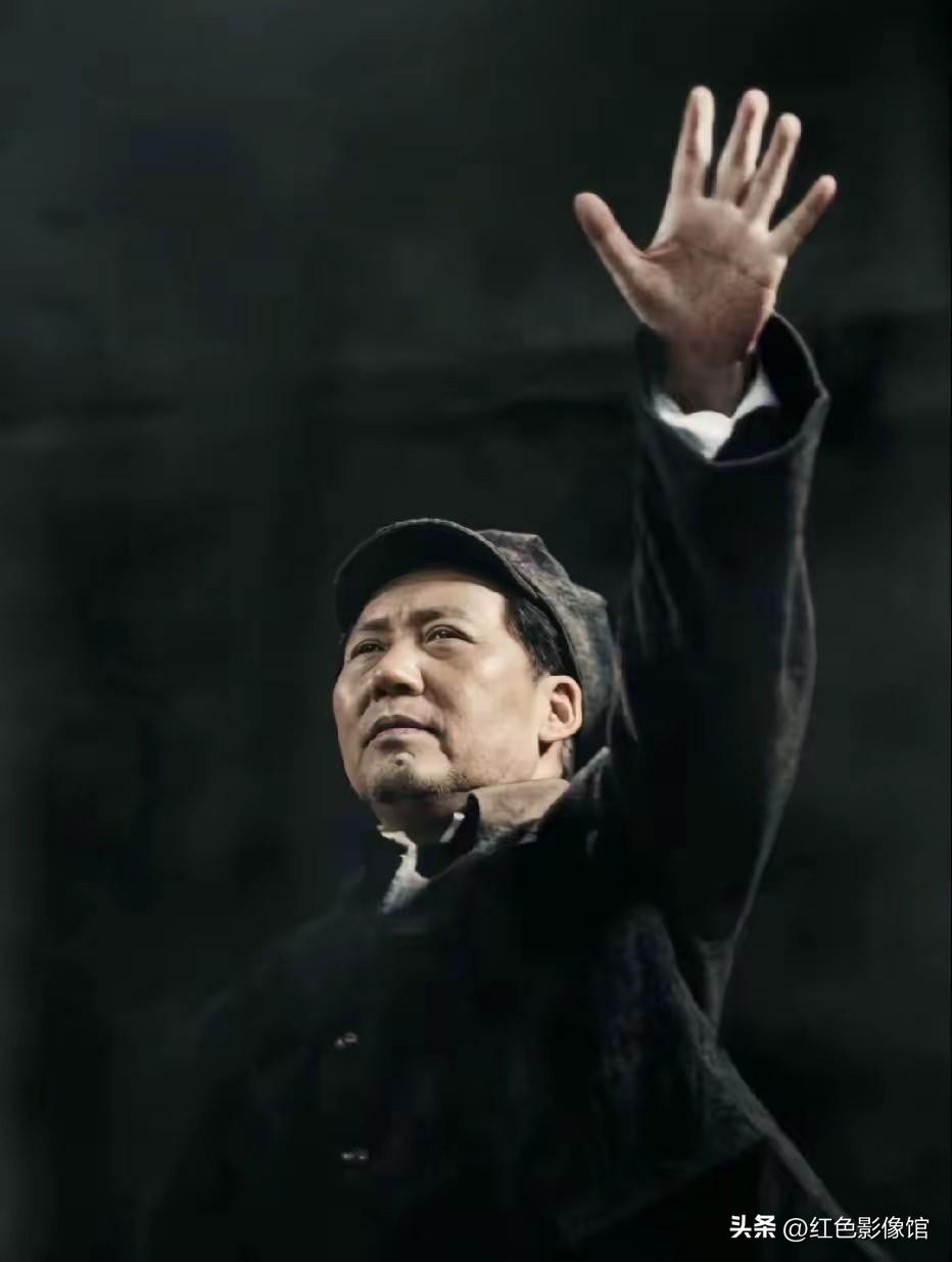 毛主席左臂高高抬起、手掌张开向前挥动，目光抬向远方，神态沉稳厚重，塑造出领袖向群