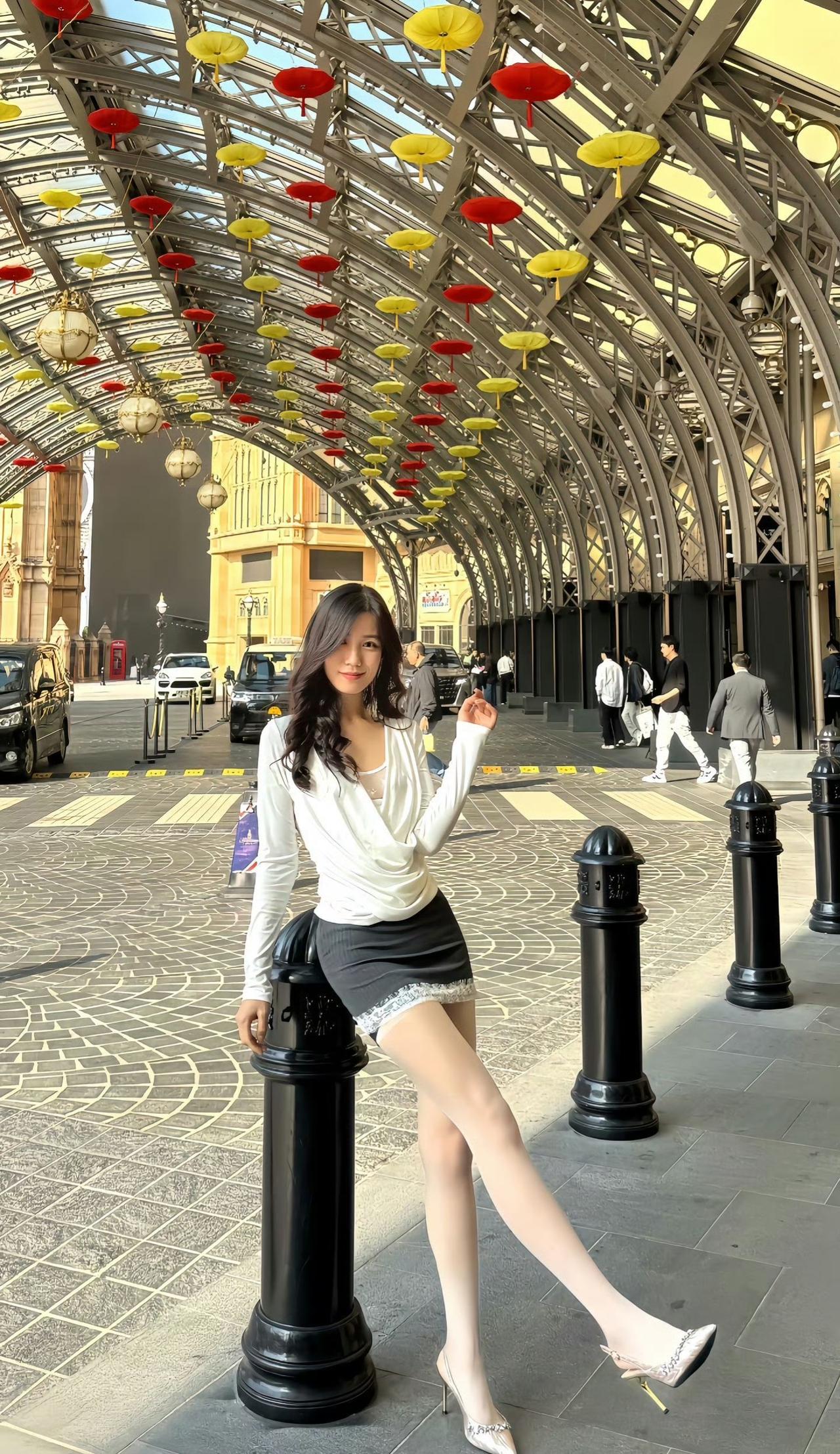 这套穿搭在城市建筑背景下特别有都市精致感！白色缎面上衣自带高级光泽，黑裙的蕾丝边