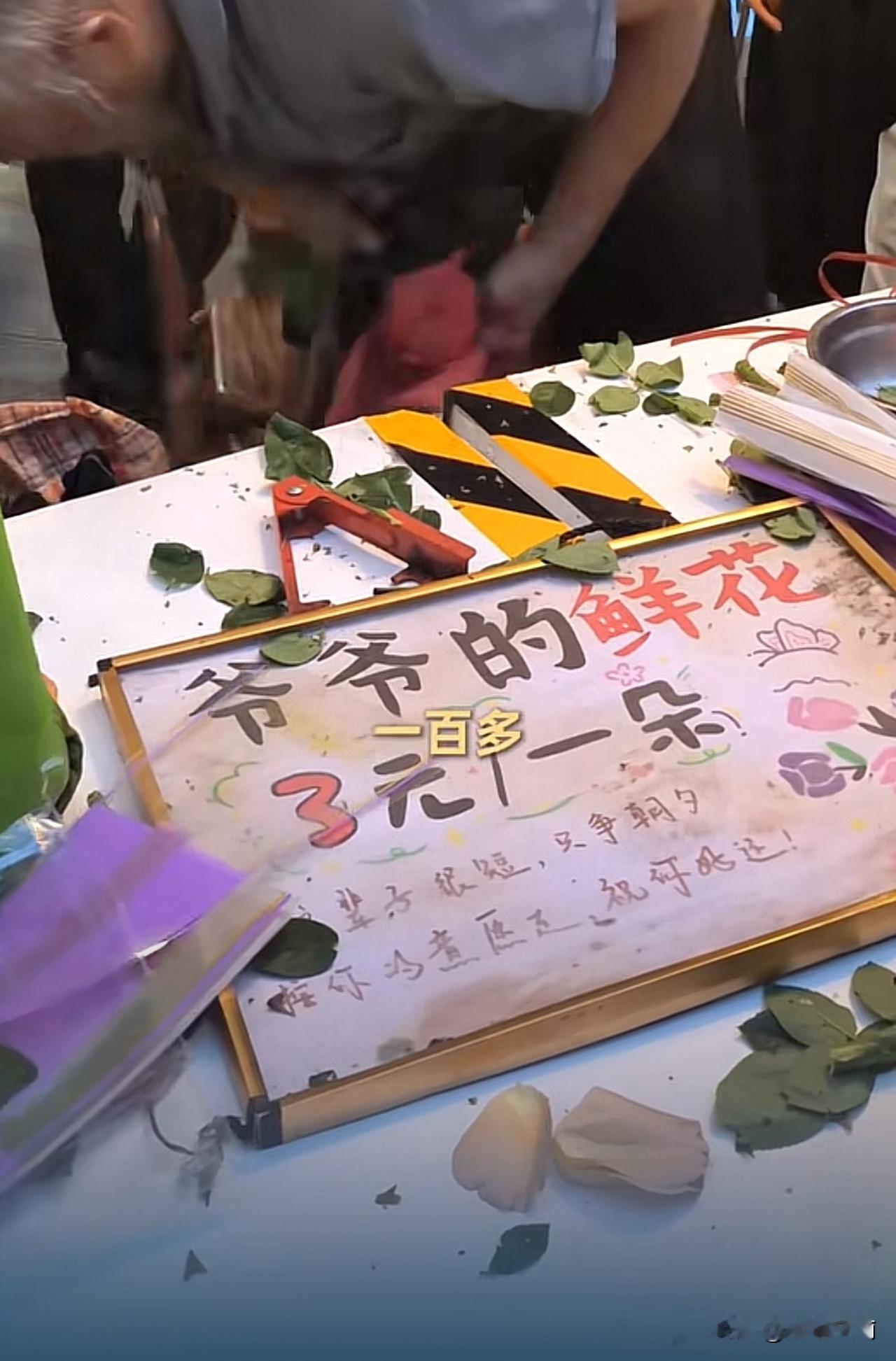 73岁，深夜11点，马路牙子上，一个老人蜷缩着睡着了。旁边摆着一堆没卖完的花。