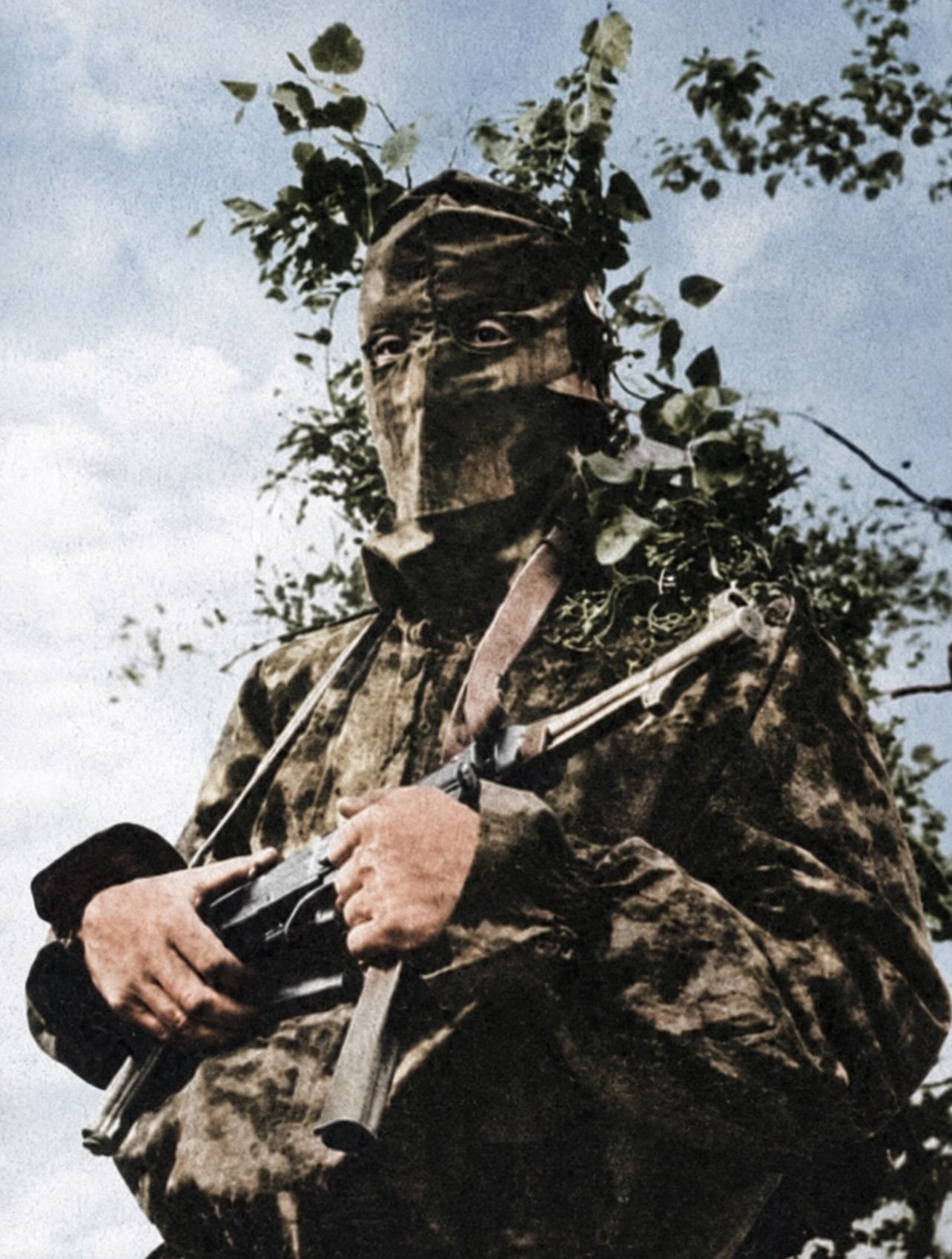 1943年，一名德军侦察兵佩戴着布制迷彩面罩，身着带有天然植物纹样的罩衫。 ​​