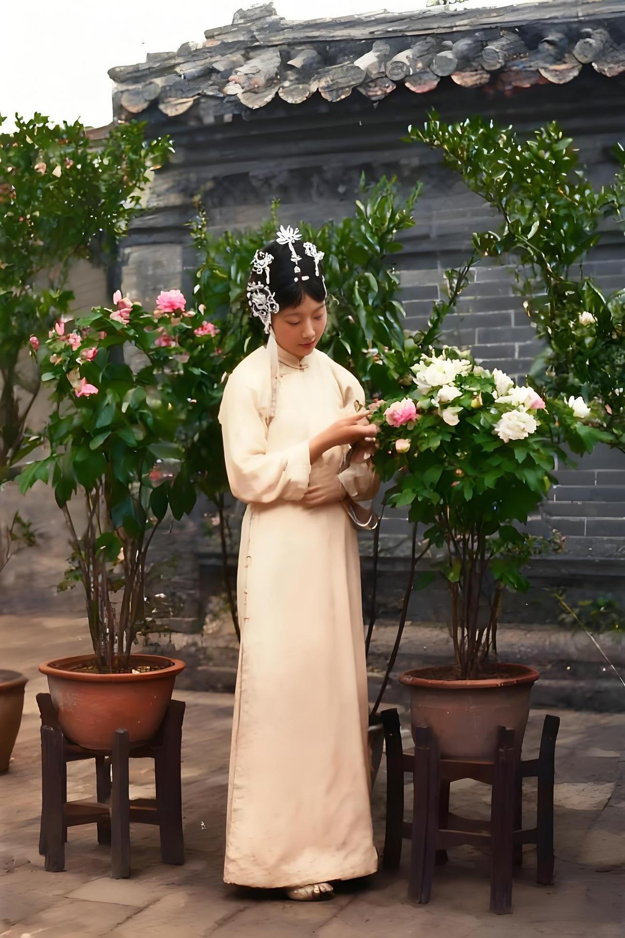 照片呈现出婉容身处中式庭院的场景。她身着素雅的传统旗装，衣料色调柔和，尽显华贵质