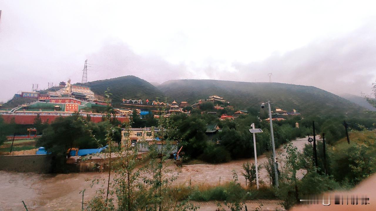 湟水奔涌，漫过滩岸，云雾轻笼着山间殿宇。
远山静默，红墙金顶安坐于此。
途经此地