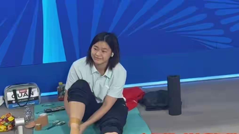 全红婵坐在今日比赛训练场上，熟练的敷着脚伤，工作人员也在一边针对性帮助她激活受伤