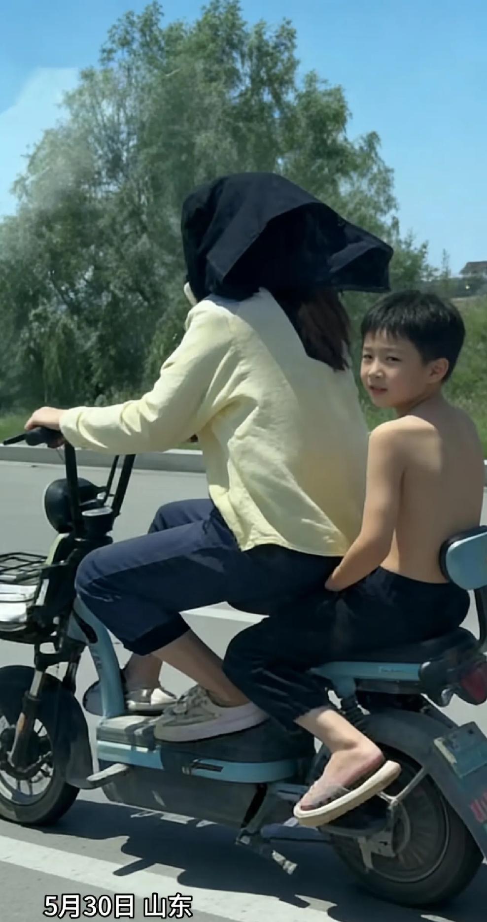绝对亲生的！
5月30日，山东，妈妈骑着电动车带着儿子，因为太阳大，妈妈怕晒，要