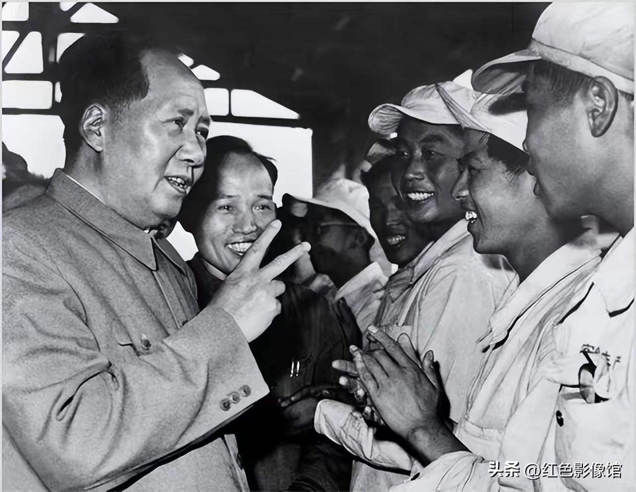 这是毛主席深入工厂车间视察时的珍贵历史黑白照片：
毛主席身着中山装，面带笑容，对