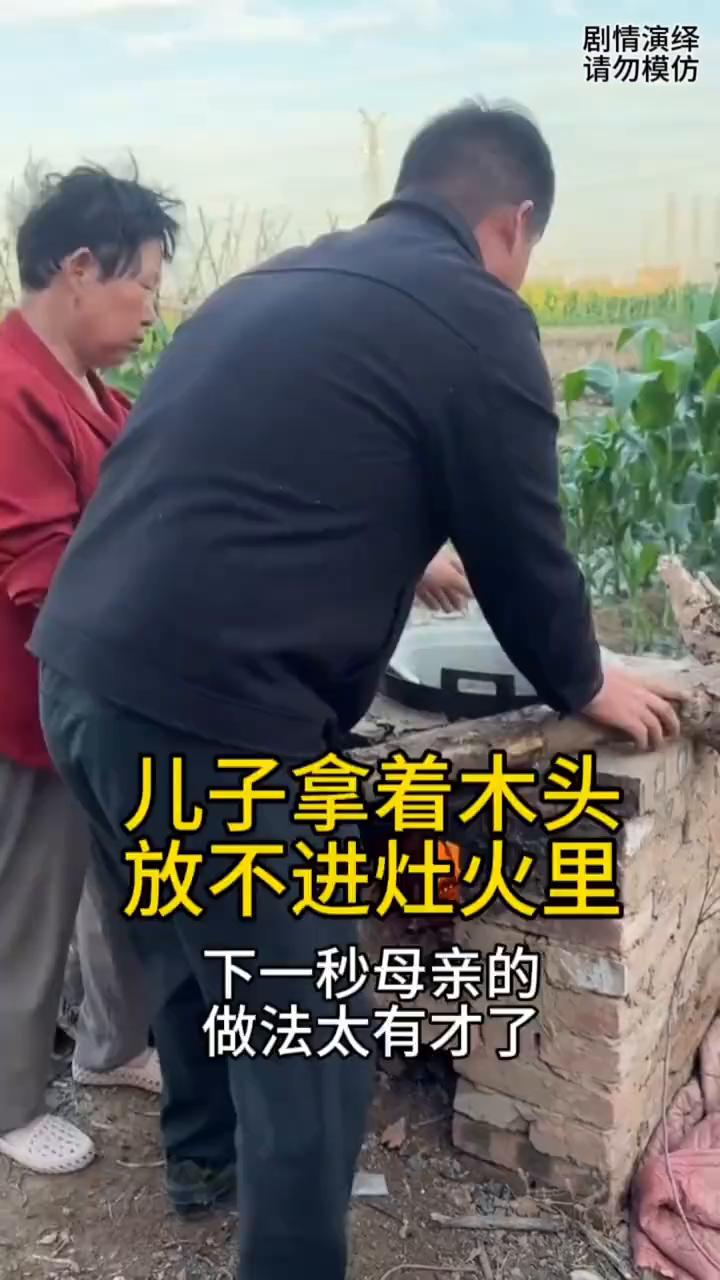 儿子拿着木头放不进灶火里，下一秒母亲的做法太有才了。
母子两个正在做中午饭，这时