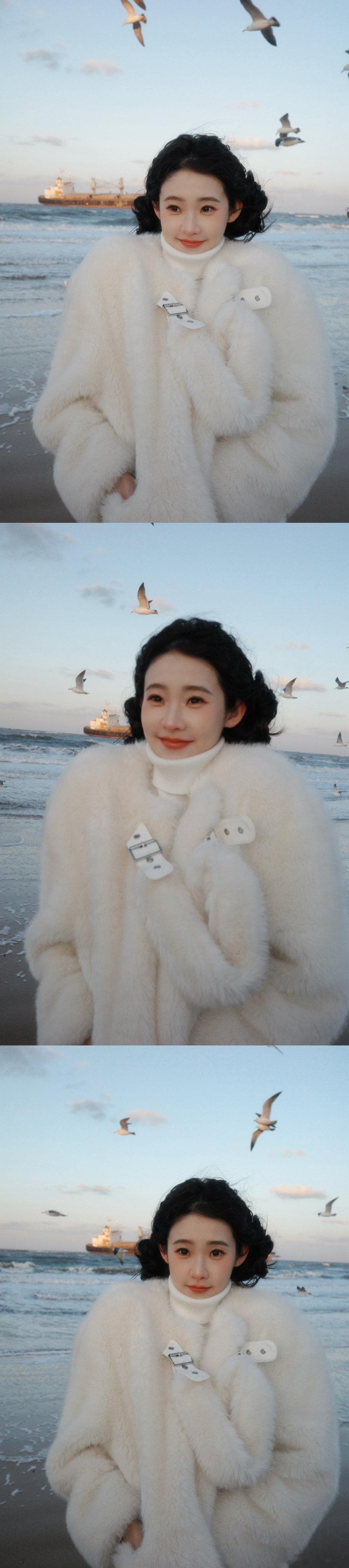 张艺凡咋萌成萨摩耶了 海风把她的绒毛帽吹出蓬松的涟漪，像萨摩耶奔跑时抖动的颈毛。