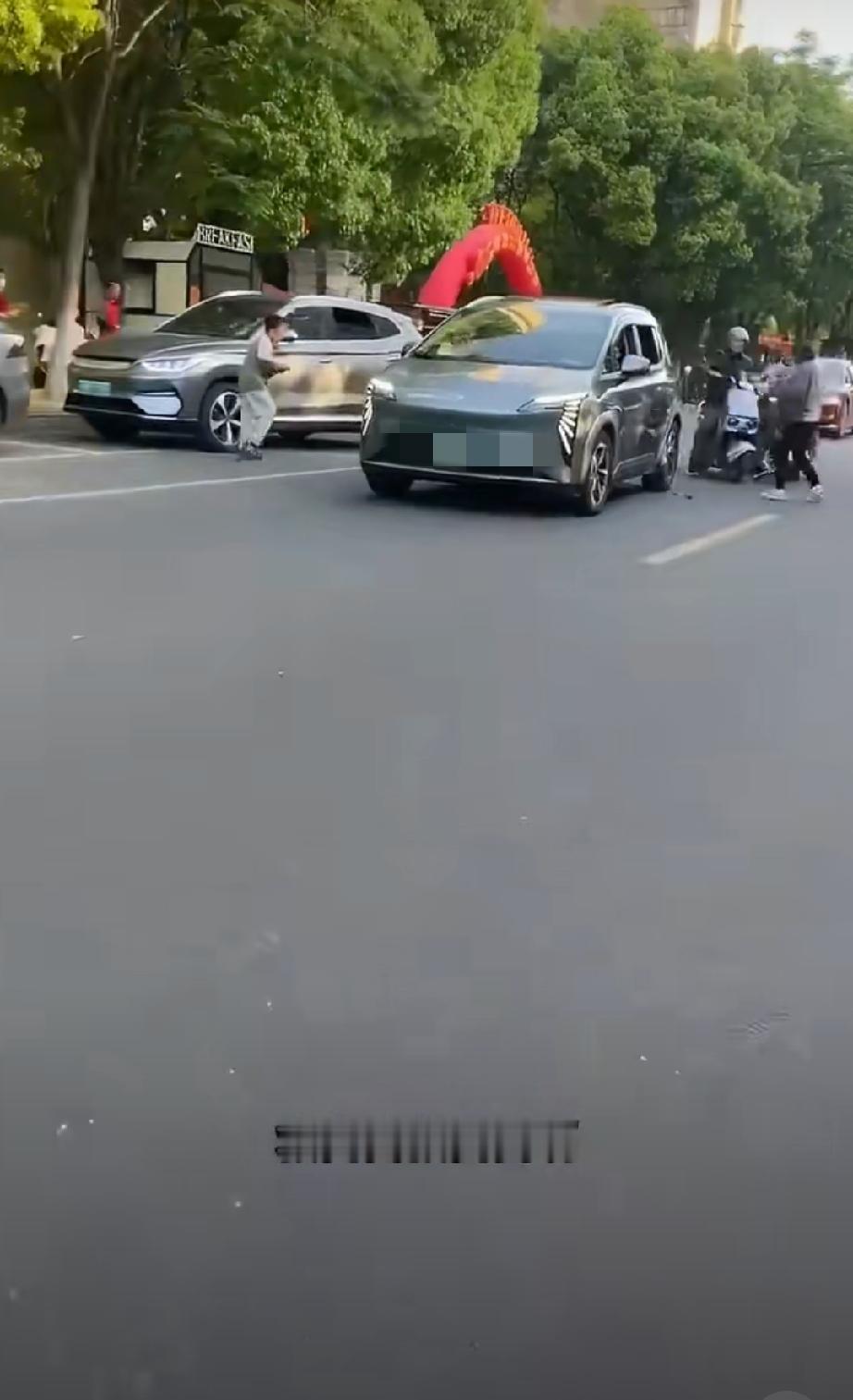 未牵绳的宠物狗被马路上的车辆压在车轮下，狗主人情绪崩溃大叫，一旁的儿子被狗咬伤也