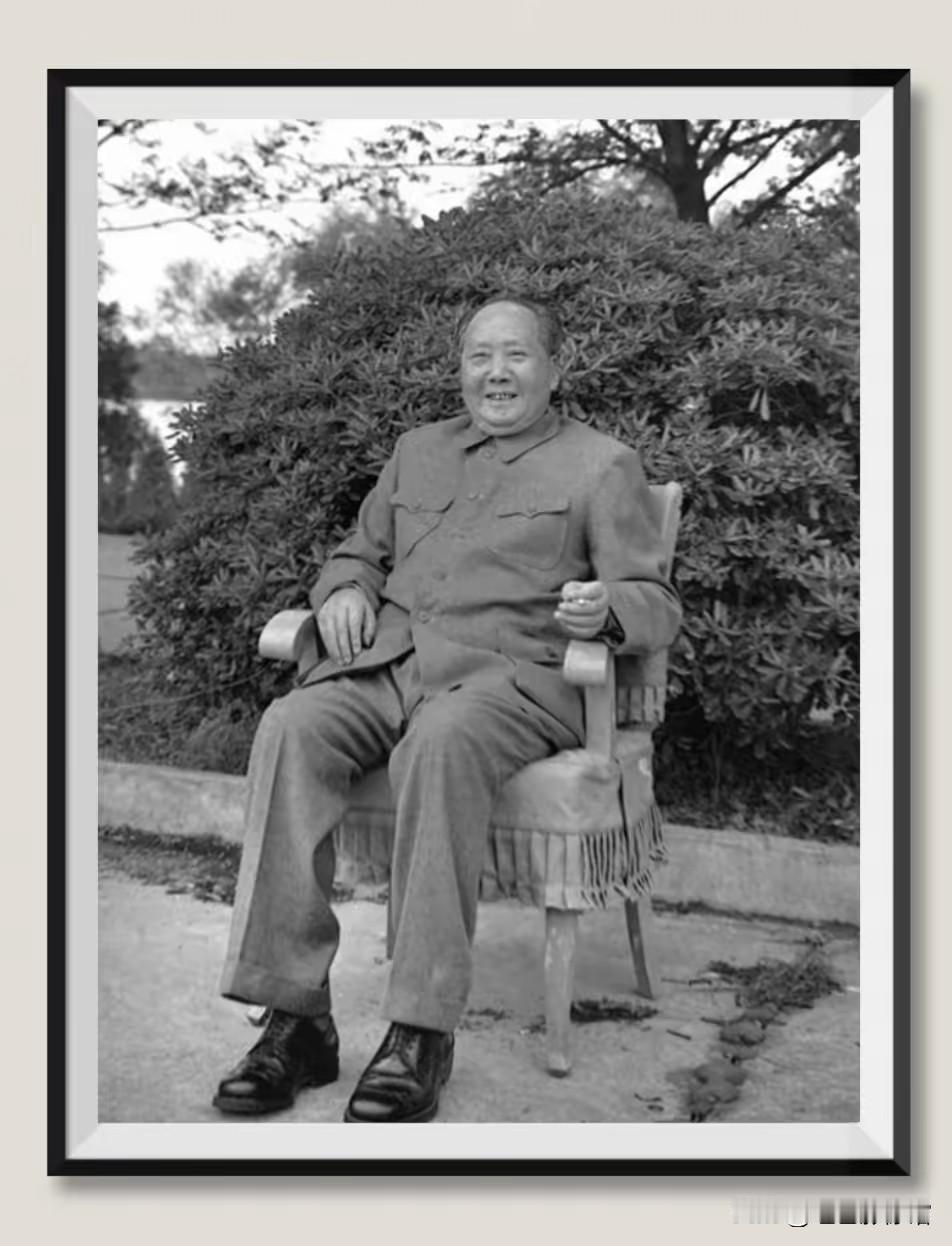 照片中，毛泽东同志身着中山装，坐在户外的扶手椅上，面带笑容，神态轻松自然，左手夹