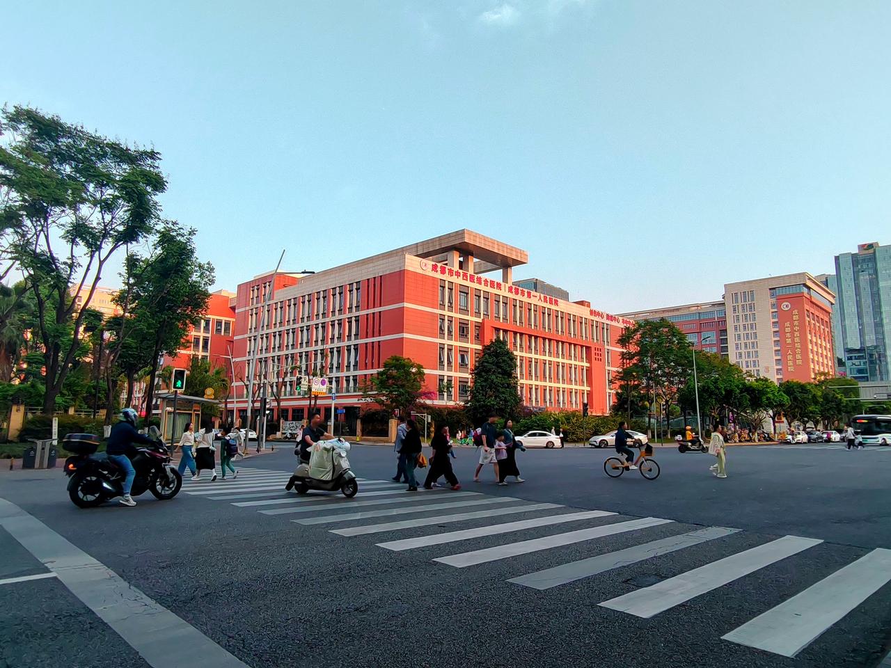 路口的人流与车流向着各自的方向奔赴，红墙高楼在晴天下格外鲜亮，城市的烟火气就这样