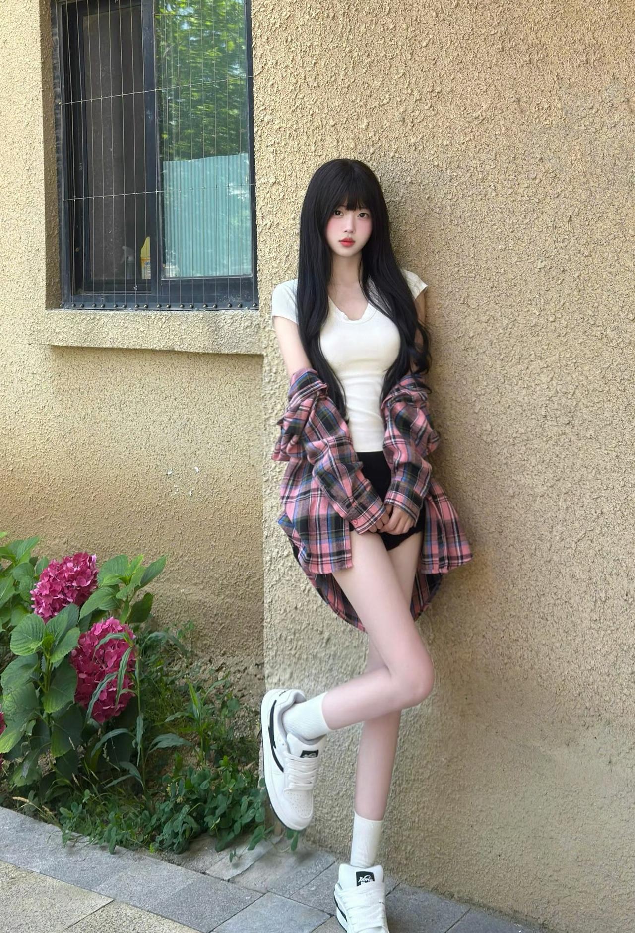 穿着宽松格子衬衫、靠在墙边比着剪刀手的女孩，真的太有那种邻家学妹的清新气质了。没