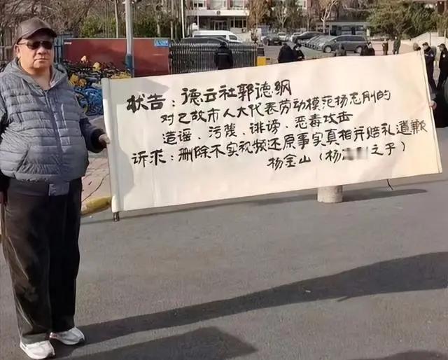 杨志刚之子杨金山，也来蹭郭德纲的流量了。他拉起横幅，要状告老郭造谣，污蔑，诽谤和