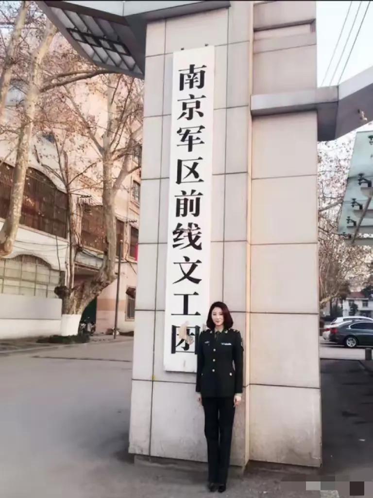 2015年，江苏，南京军区前线文工团前，一位穿着军装的美女在牌匾前留影，虽然照片