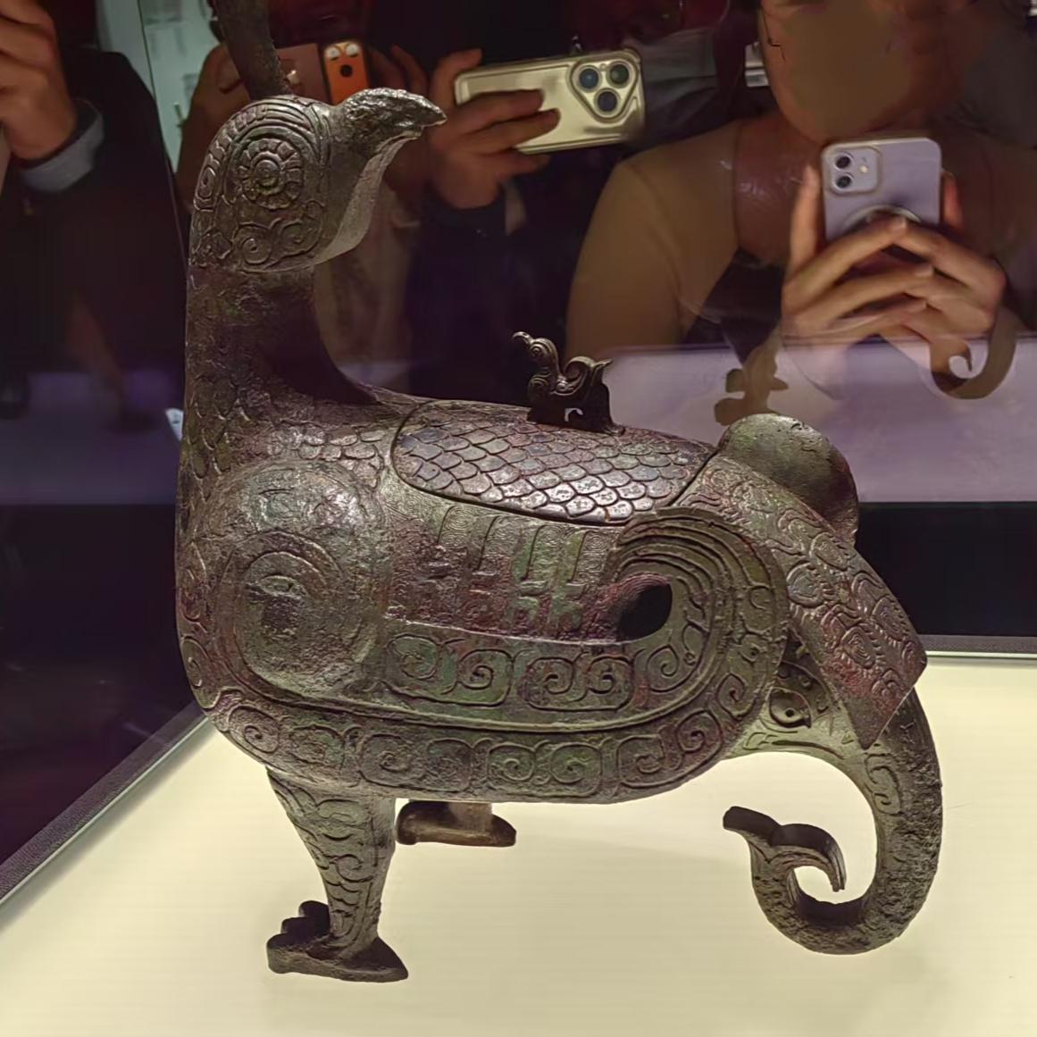 在山西博物院展厅，众多游人驻足在"晋侯鸟尊"前欣赏拍照。

凤鸟回眸，背负小鸟，