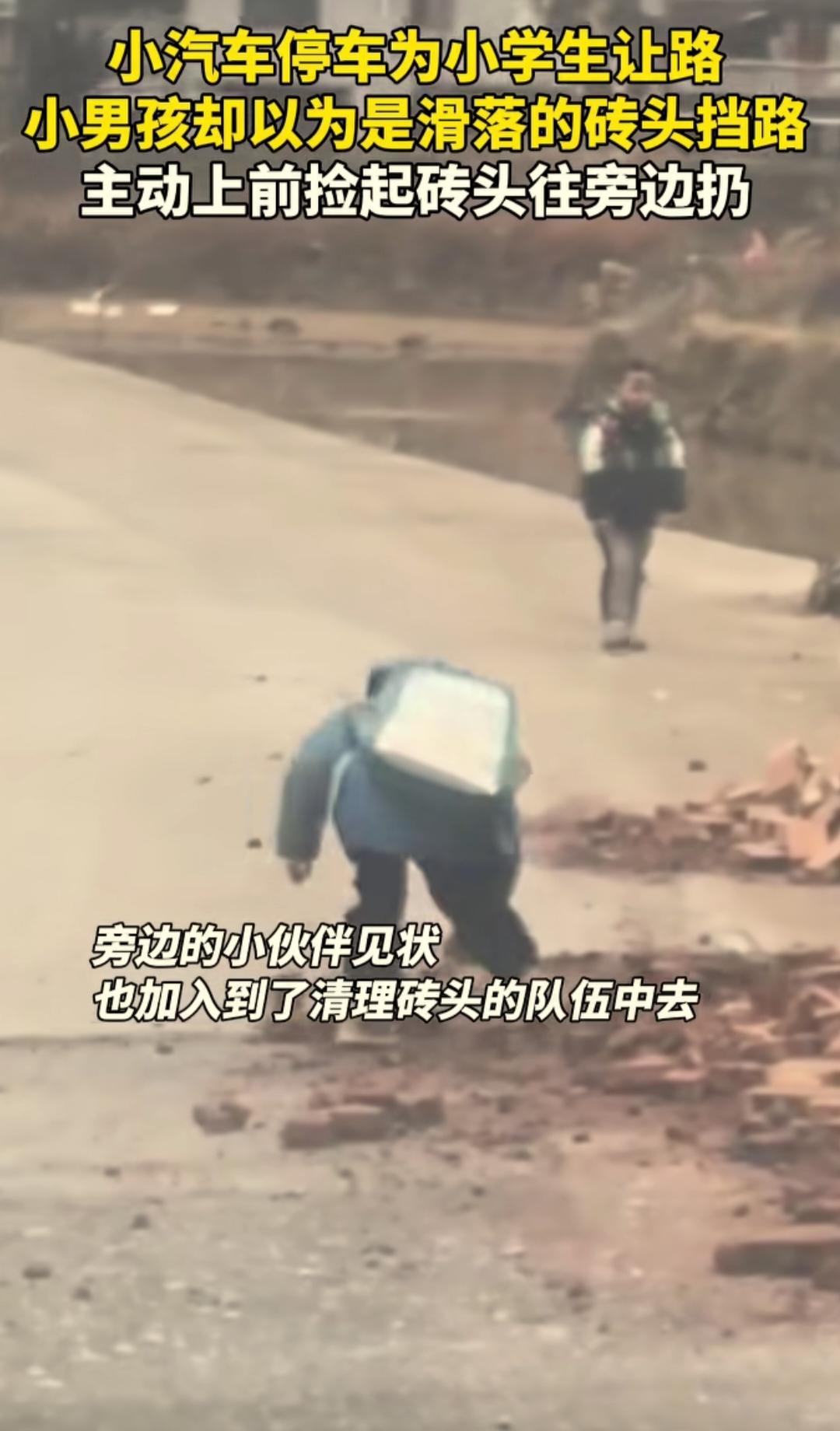 湖南一乡间公路边堆了许多砖，占了三分之一的路面。一辆小车司机看到有小学生经过，就