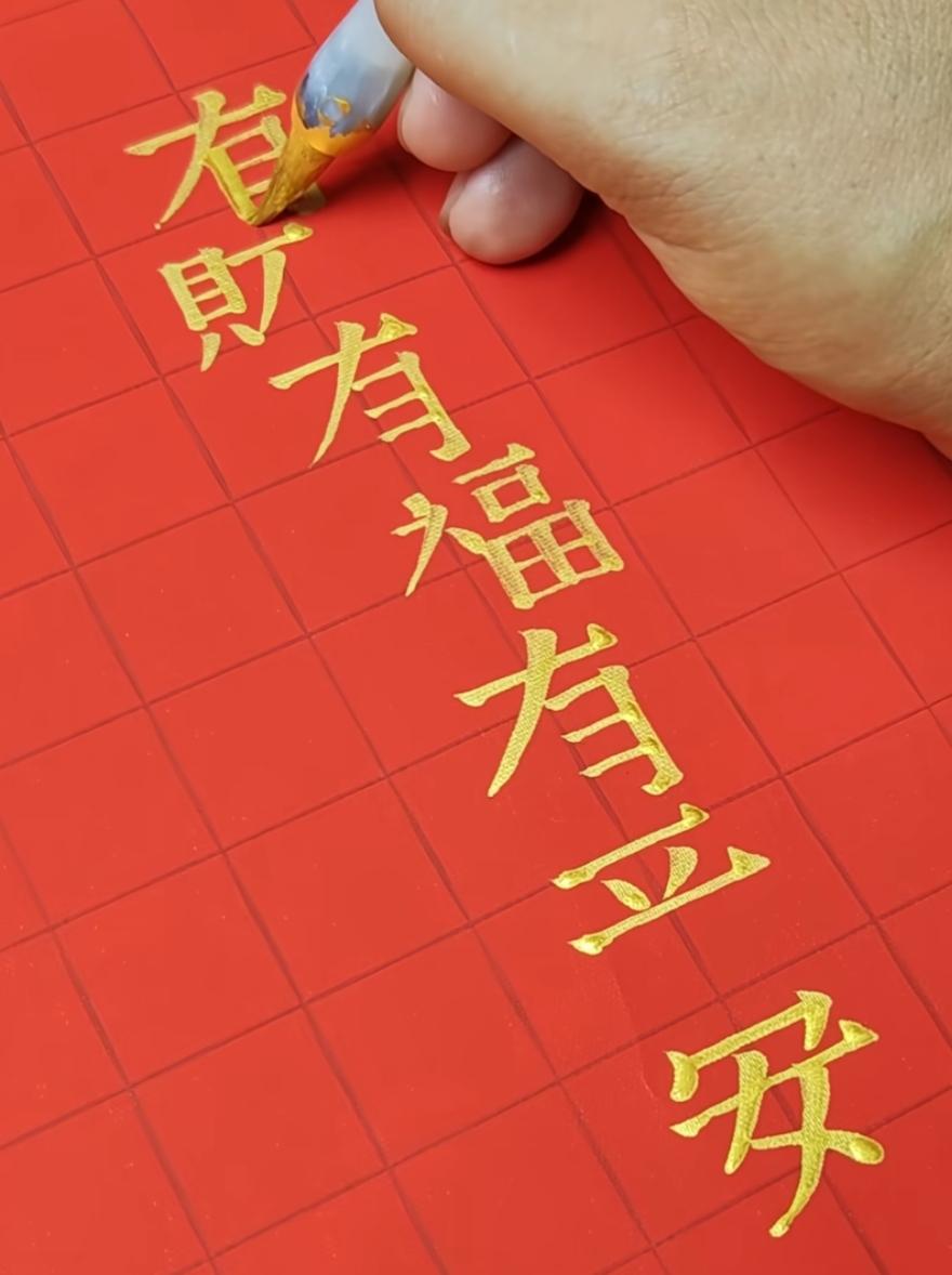 手正在红色纸上用金粉写字。9月你好，这一笔下来是几个字呢？这句话很有意义，非常好