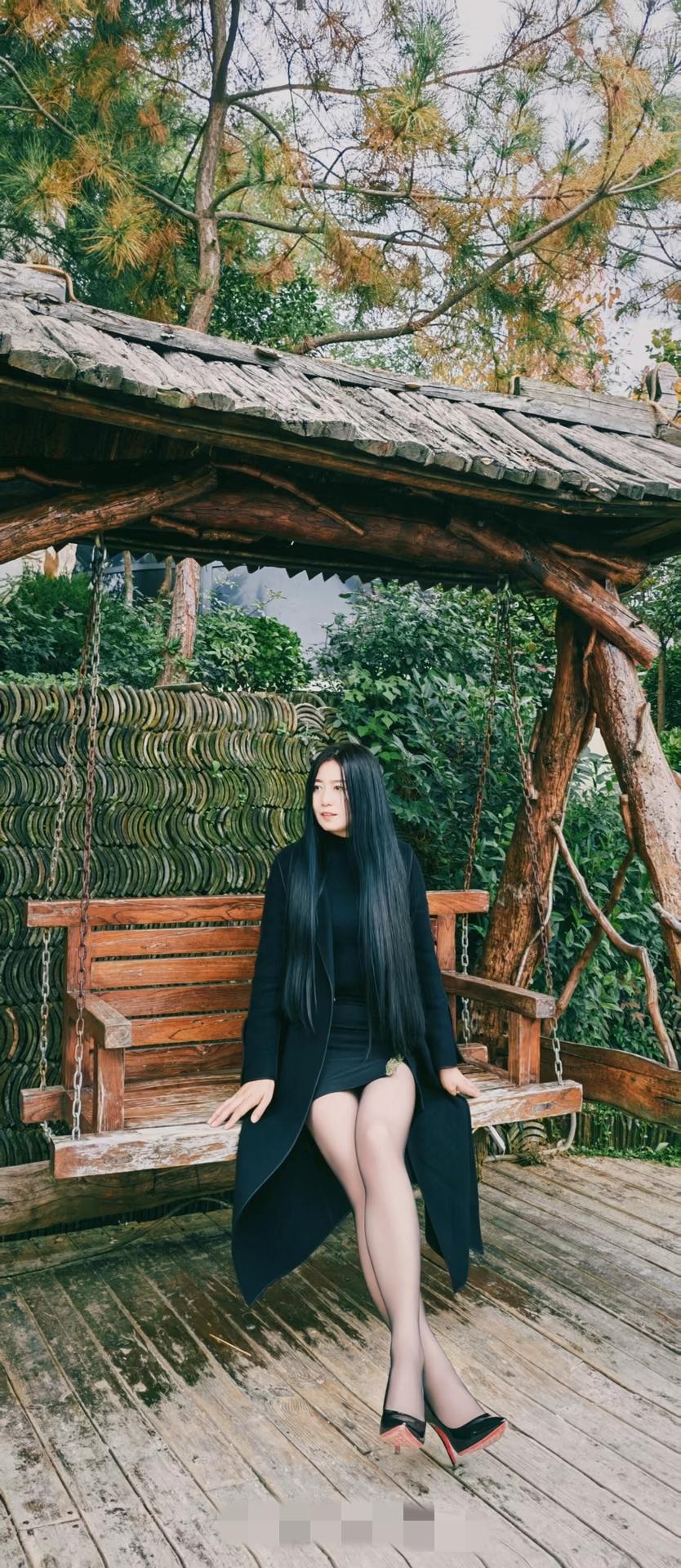 秋日森林中的优雅时光，黑衣女子坐在木制秋千上，静享宁静。御姐 高跟鞋 大长腿