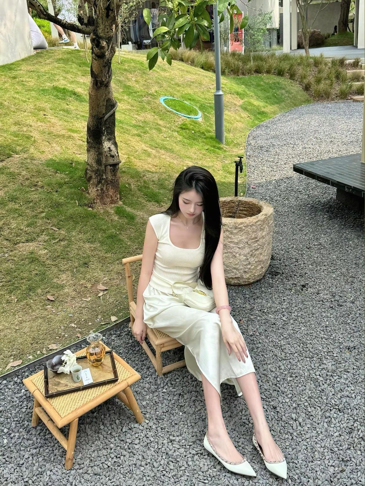 一个女孩坐在户外，穿着白色连衣裙。