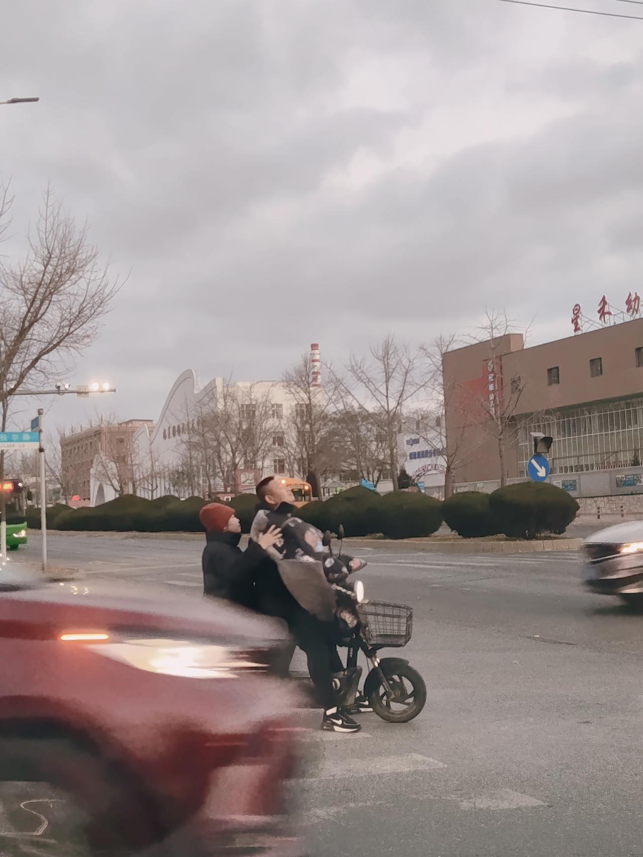 早晨在一个十字路口等信号灯，前面一对父子，父亲骑着摩托车，后面载的大概上初中的孩