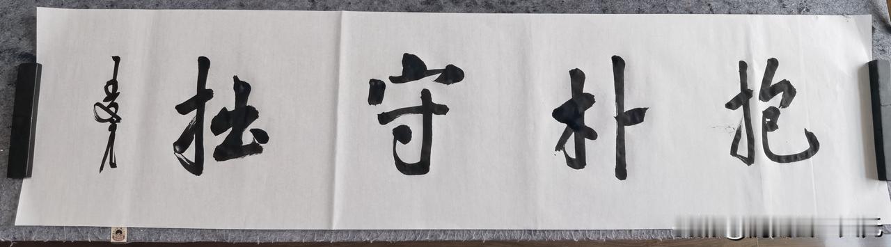 “抱朴守拙”这四字横幅，韵味十足。“抱朴”源于《老子》“见素抱朴，少私寡欲”，倡