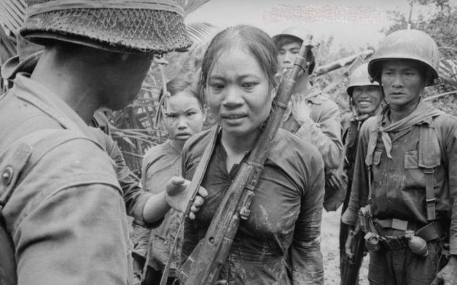 1972年，战场上躺着一个越南女兵的尸体，旁边的美国士兵扯下她的裤子、撩起她的上