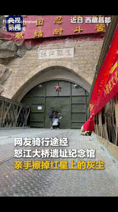 近日，在怒江大桥遗址纪念馆，骑行途经此地的兄弟俩，望见大门正中的红五星积满尘土，