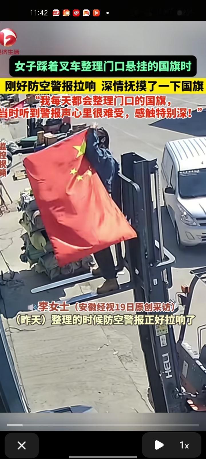 9月18日，山东滨州。女子踩着叉车整理门口悬挂的国旗，恰好防空警报拉响，深情抚摸