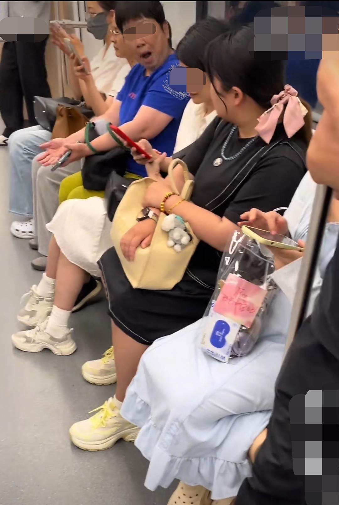 6月10日，上海一地铁上。疑似黑衣女子就座时占用空间较大，身旁蓝衣女子觉得自身乘