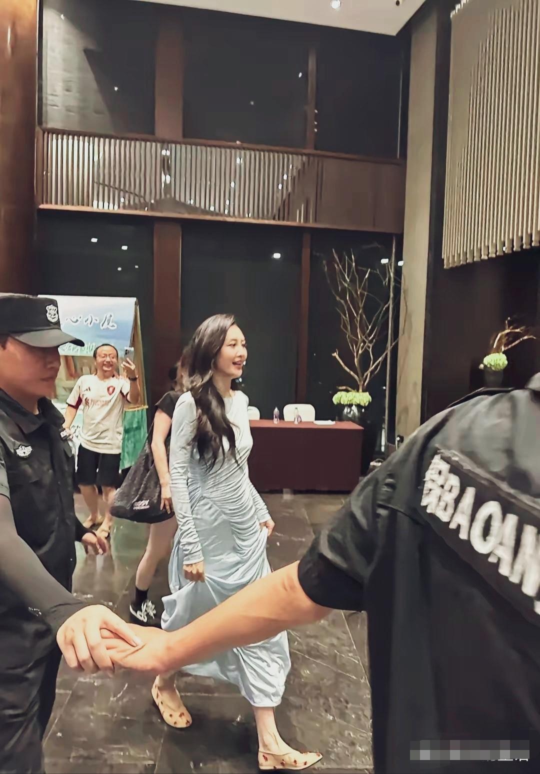 王鸥七夕晚会后台抓拍，一身冰蓝色褶皱长裙，平底鞋出行，眉眼柔和。
安保人员牵手护