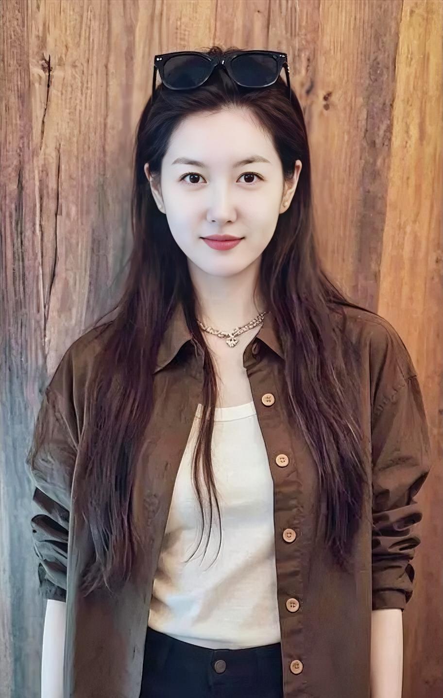《木色时光》

棕衫轻披，衬着木色温厚

墨镜闲搁，长发柔垂肩头

项链微闪，笑