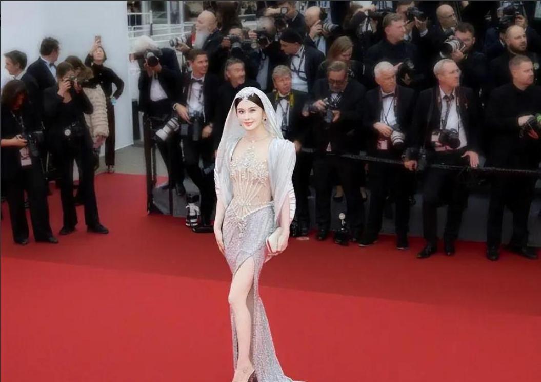 整整5分钟。 

就那么杵在戛纳的红毯台阶上，死活不走。

身上那点薄纱，风一吹