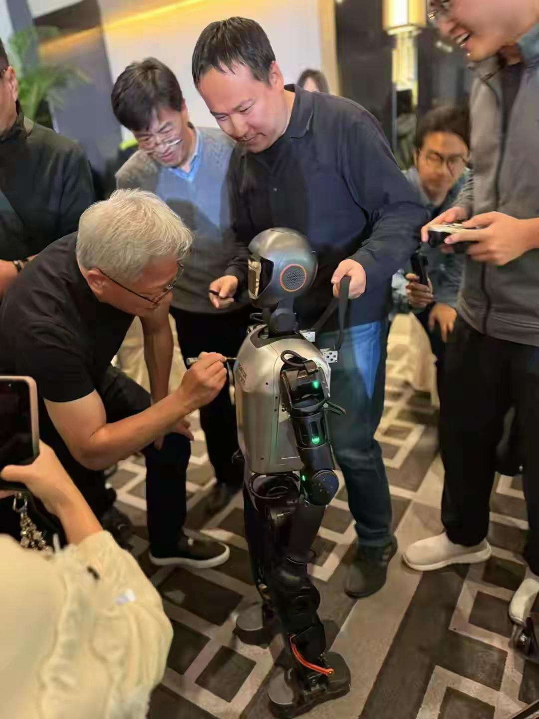 黄仁勋弄机器人，一大群人围观，优秀的人认真工作的时候样子最帅了。