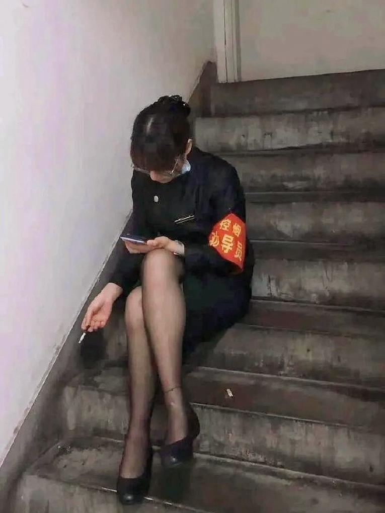 今天在朋友圈看到这张图，群里直接吵翻了！
戴着“控烟劝导员”的红袖章，自己却在楼