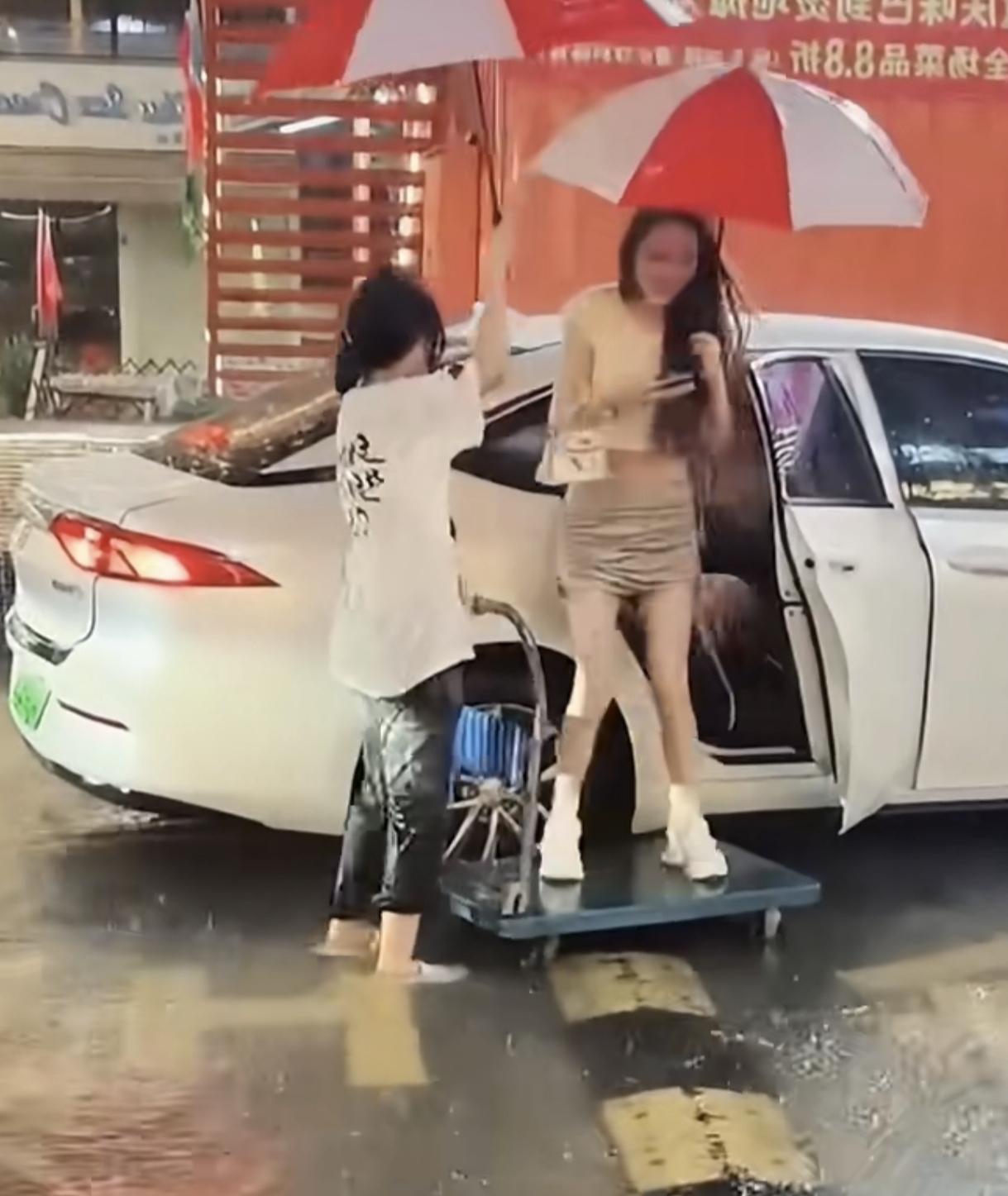 女子打扮的很精致去上班
不料，却遭天降暴雨
就在她下车的这个时候，闺蜜拉着推车出