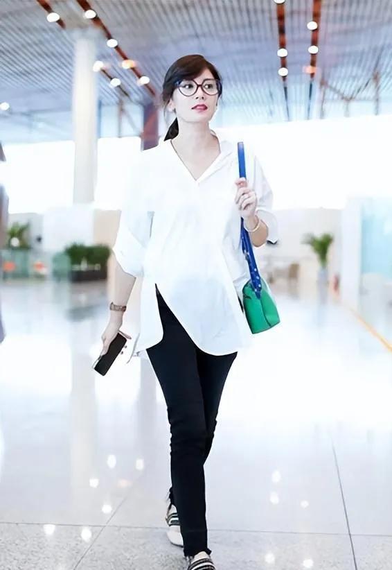 50岁贾静雯的机场穿搭太绝了！✨
白衬衫+小黑裤，简约又高级，亮绿包包和穆勒鞋瞬