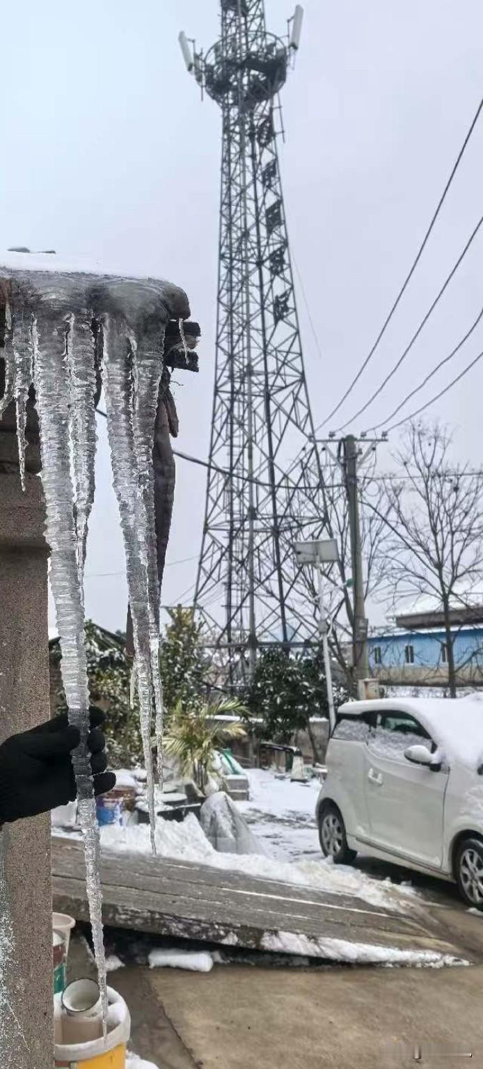 这场雪是真够“硬核”的——你看这冰溜子，跟胳膊差不多粗，挂在房檐上跟水晶柱似的，