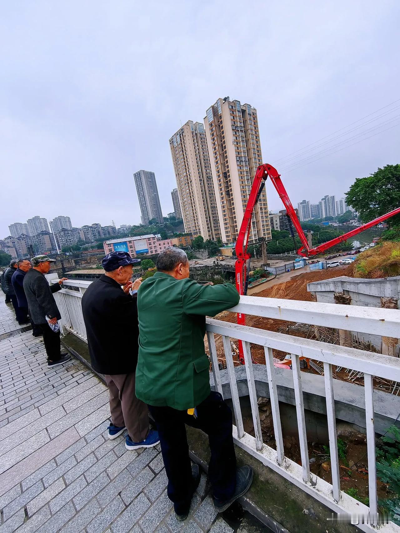 正在建设中的万州区北滨路明镜滩下穿道工程，施工现场水泥罐车长臂输送管车，正在浇灌