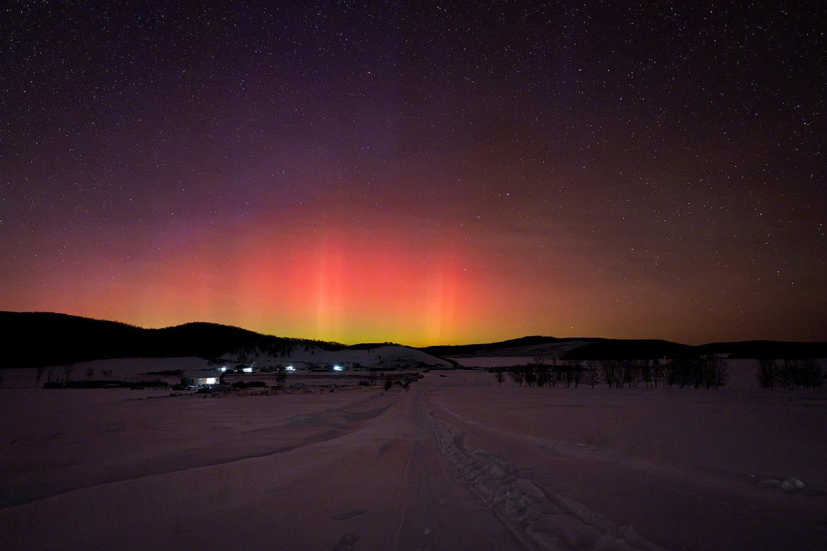 地磁暴席卷北境的夜晚，极光从雪野与群山之后缓缓升起。绿色的光带贴近地平线铺开，红