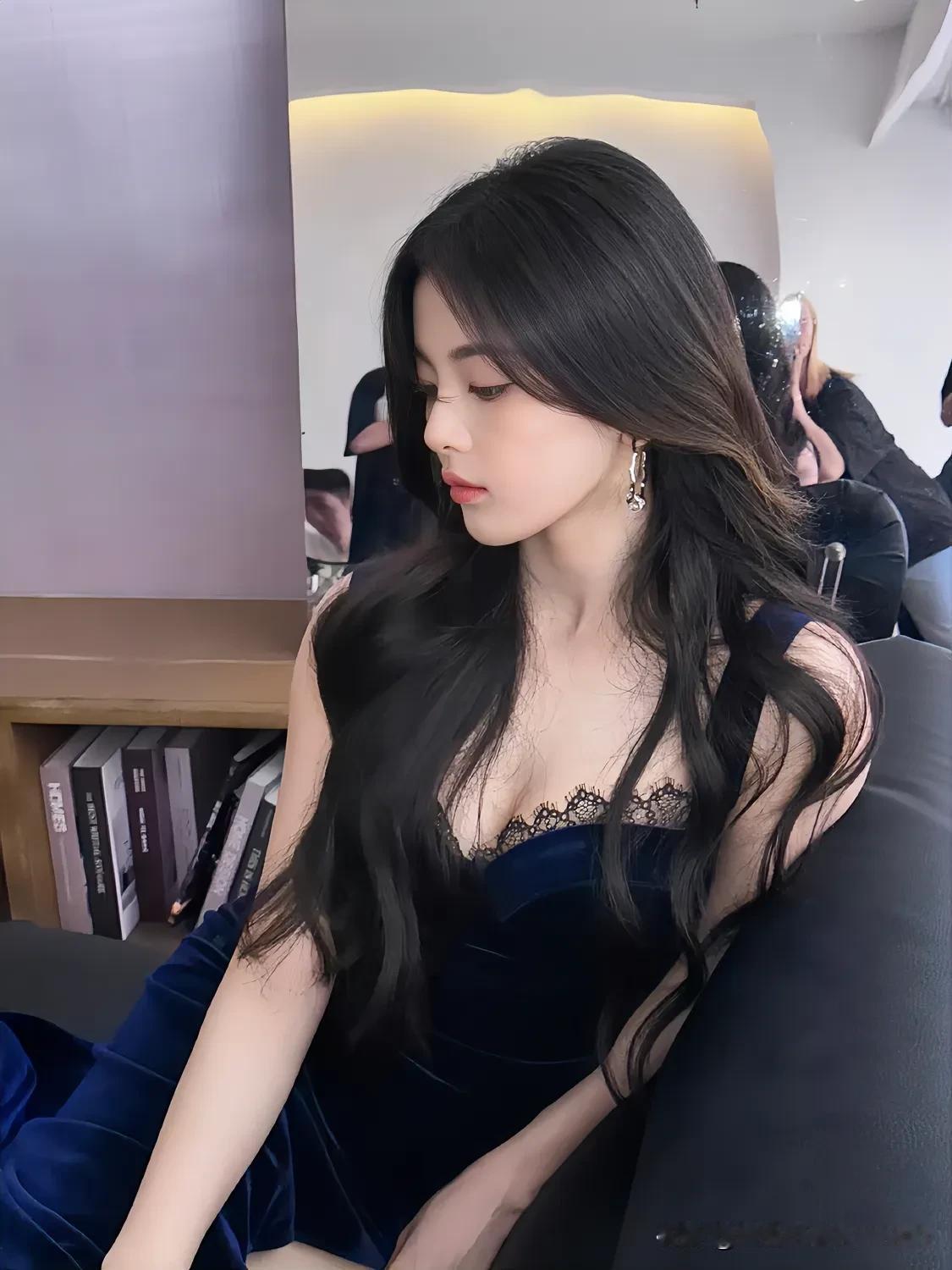 杨超越静静倚坐，一袭深蓝丝绒裙，蕾丝点缀，尽显优雅性感。乌黑长卷发自然垂落，勾勒