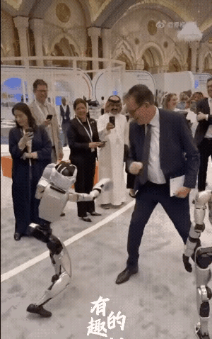 宇树的机器人陪着默茨一行成员打拳击，一招一式，闪躲腾挪，有模有样，这是戴着拳击手