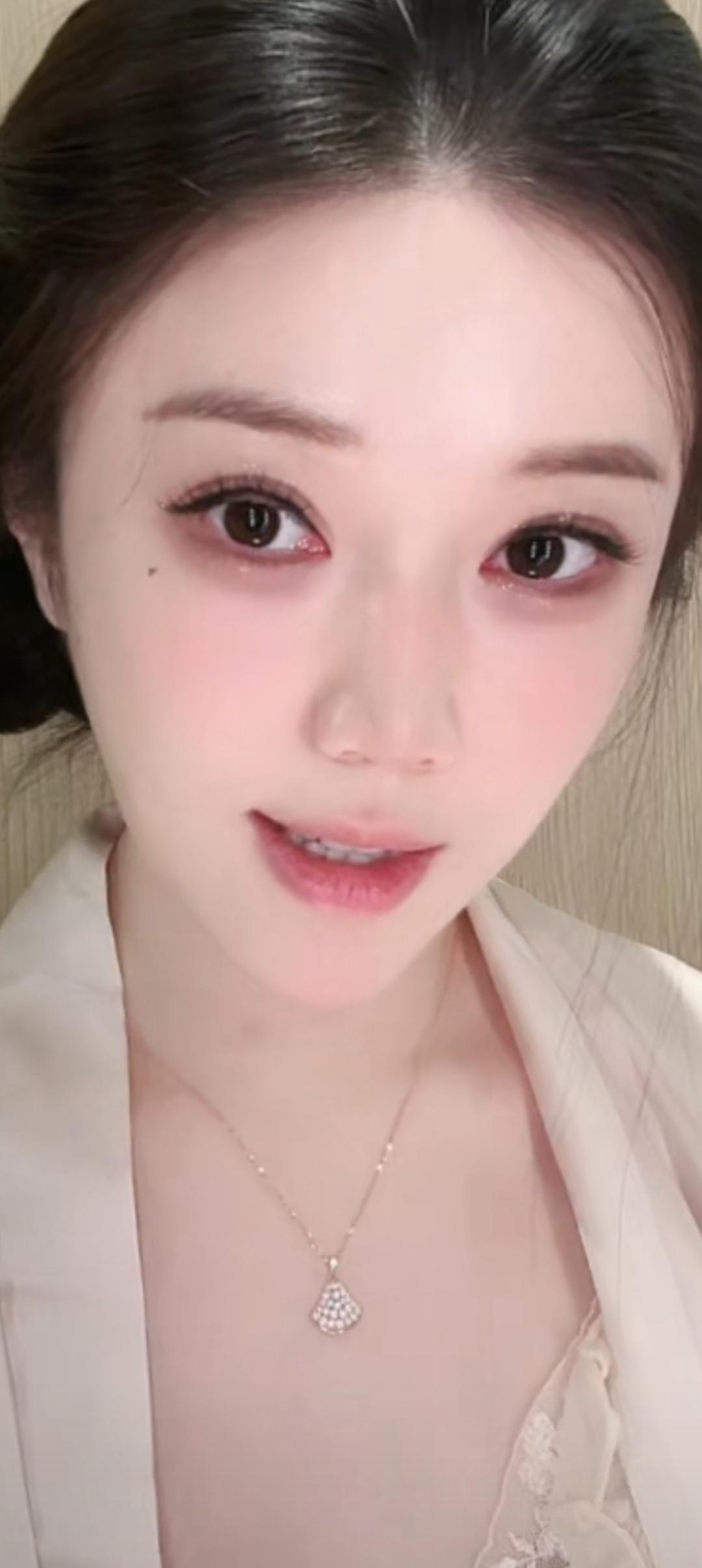 这位美女穿着白色外套，佩戴精致项链。