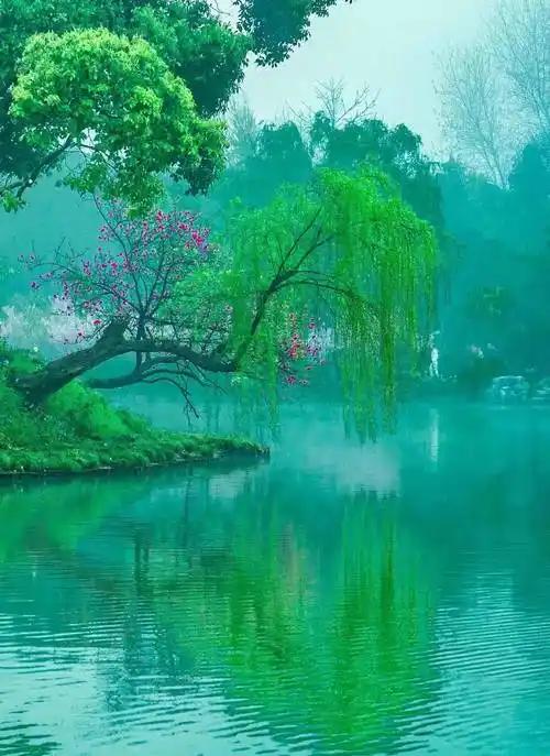 下联：庭前日暖吻红桃

上联“水畔烟轻缠碧柳”描绘水边轻烟缭绕、碧柳依依的朦胧柔