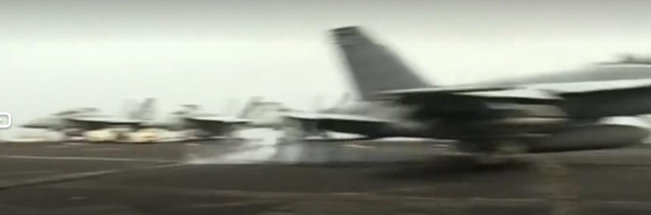 航母甲板上，F/A-18战机在引导员指令下蓄势待发，腾空而起的瞬间尽显威慑力。与